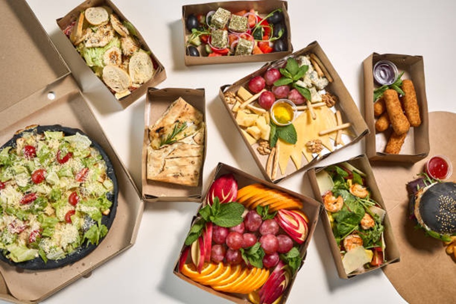 Eco-friendly cardboard boxes filled with fresh salads for sustainable office catering