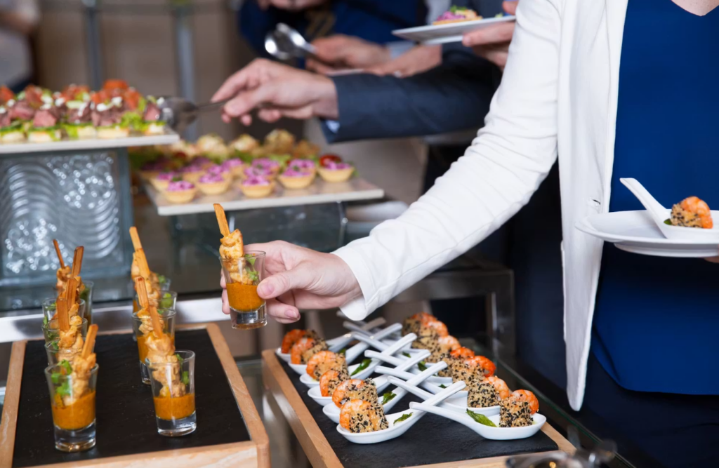 Uniformed catering server plating appetizers at a full-service corporate event