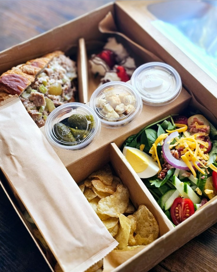 Employee holding a boxed lunch with sides at a daily office catering delivery