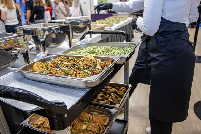 Catering staff carrying a large tray of food for an office drop-off delivery