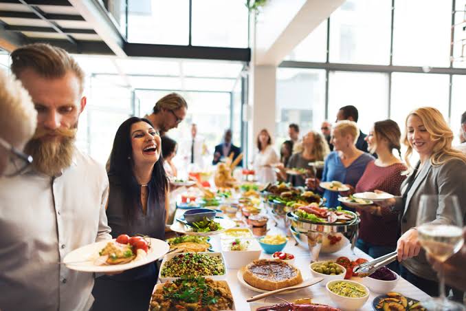 Office team laughing together at a catered lunch buffet